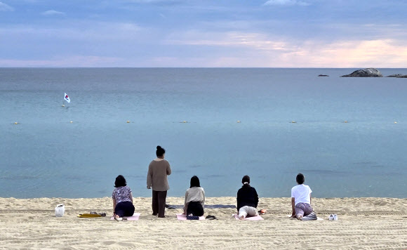 강원 강릉지역이 폭염경보 속에 이틀 연속 열대야를 기록한 1일 경포해변 백사장에서 주민들이 요가하며 열대야의 아침을 맞고 있다. 밤사이 강릉의 최저기온은 29.7도를 기록했다. 2025.7.1  연합뉴스