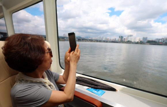 1일 정식 취항을 앞두고 시범운항에 나선 한강버스에 탑승한 시민이 출발 전 한강과 마포 일대를 촬영하고 있다. 한강 유역에 처음 도입되는 친환경 수상 대중교통수단인 한강버스는 9월 중 정식운항을 통해 마곡~망원~여의도~옥수~압구정~뚝섬~잠실(마곡~여의도~잠실 급행 병행 운영) 7개 선착장, 약 31.5km의 거리를 운항할 예정이다. 2025.7.1  연합뉴스
