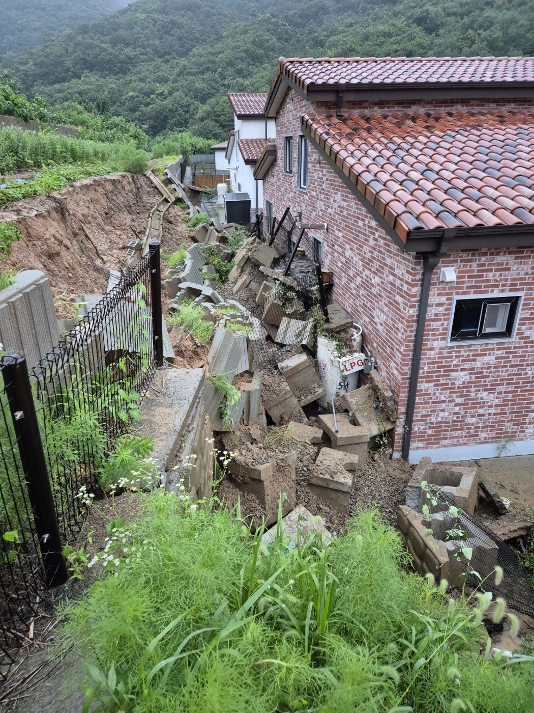 LPG통 위로 무너진 옹벽  17일 충북 음성군 음성읍의 한 주택 뒷마당에 200㎏ 용량 LPG 용기가 폭우로 무너진 옹벽에 묻혀 있는 모습. 가스가 소량 누출됐으나 긴급 안전조치로 추가 피해는 발생하지 않았다.
음성 연합뉴스