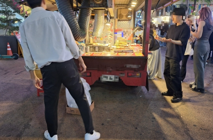 지난 12일 서울 마포구 홍대의 번화가인 ‘레드로드’에 자리한 이동형 노점에서 시민들이 닭꼬치를 사 먹고 있다. 독자 제공