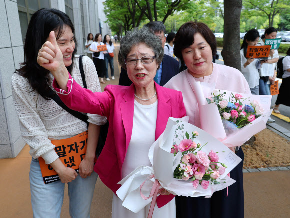 61년 전 성폭행하려던 남성의 혀를 깨물어 중상해 혐의로 기소돼 유죄 판결을 받았던 최말자 씨가 10일 부산지법에서 열린 재심 선고 공판을 마친 뒤 꽃다발을 받고 엄지를 치켜 세우고 있다. 최씨는 61년 만에 열린 재심에서 무죄를 선고받았다. 2025.9.10. 연합뉴스