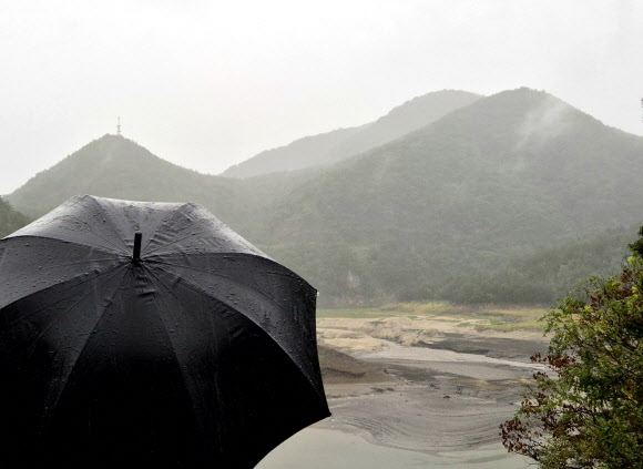13일 가뭄으로 메마른 강원 강릉시 오봉저수지 일원에 비가 내리자 시민들이 우산을 쓰고 바라보고 있다. 이날 오전 8시 기준 오봉저수지 저수율은 11.9%로 전날보다 0.4%포인트 올랐다. 2025.9.13. 연합뉴스