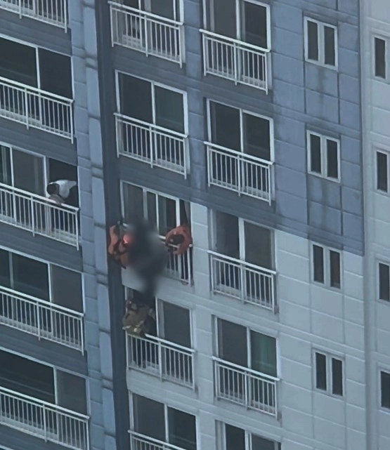 고층 아파트 난간에 젊은 여성이 거꾸로 매달려 있다가 119 구조대원들에게 극적으로 구조됐다. 연합뉴스