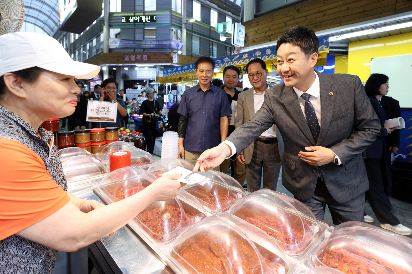 김진경 의장이 삼미시장 점포를 방문해 상인에게 지역화폐로 젓갈을 직접 구입하며 애로사항을 듣고 있다. (사진=경기도의회)