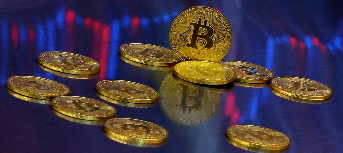 비트코인 모형이 놓인 바닥에 코인 시세 그래프가 비치는 모습. 연합뉴스