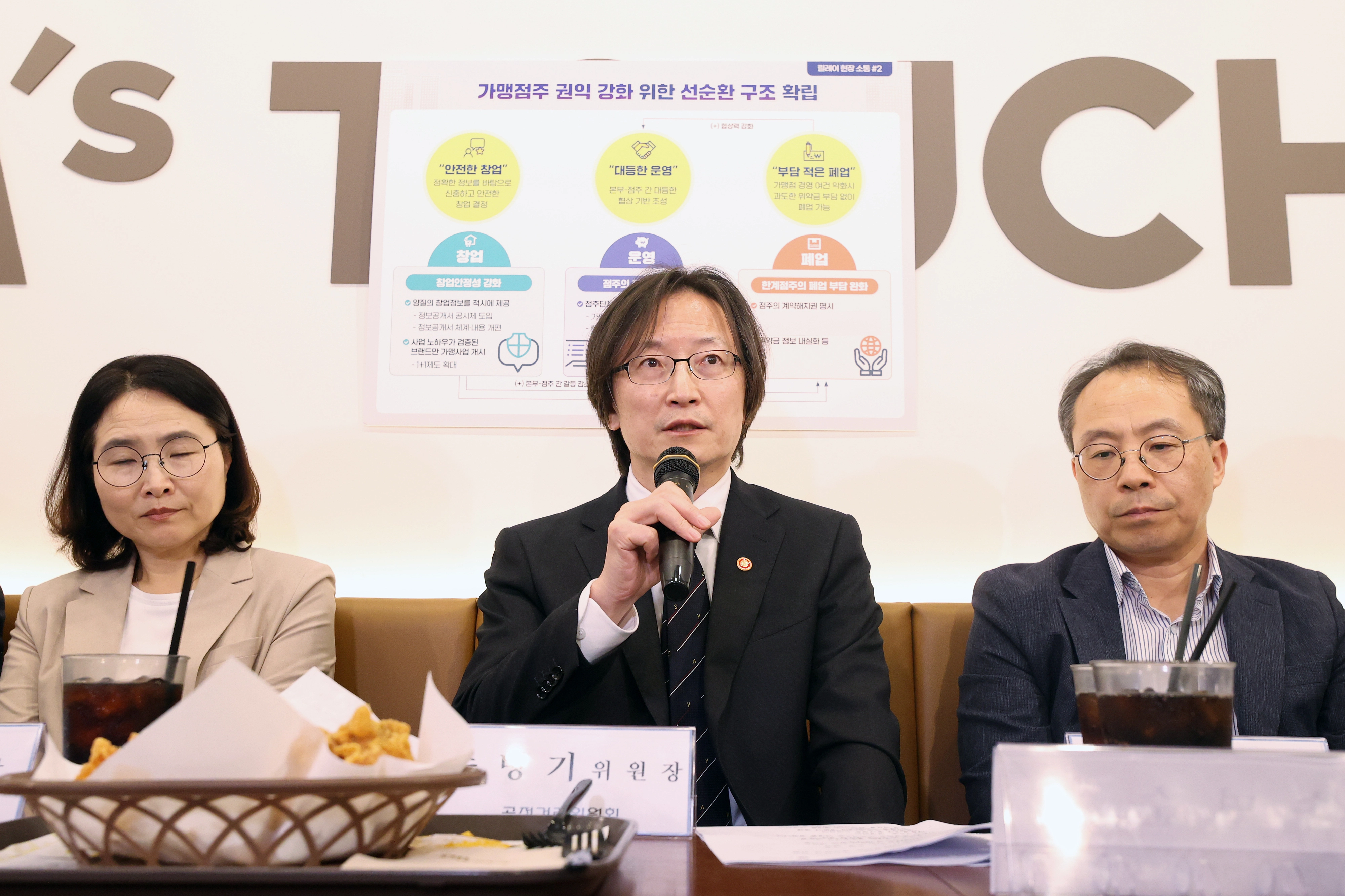 주병기 공정거래위원장이 23일 서울 마포구의 한 맘스터치 매장에서 진행된 가맹업계 관계자들과의 간담회에서 인사말을 하고 있다. 왼쪽부터 공정위 정희은 대변인, 주 위원장, 홍형주 기업협력정책관. 2025. 9. 23. 연합뉴스