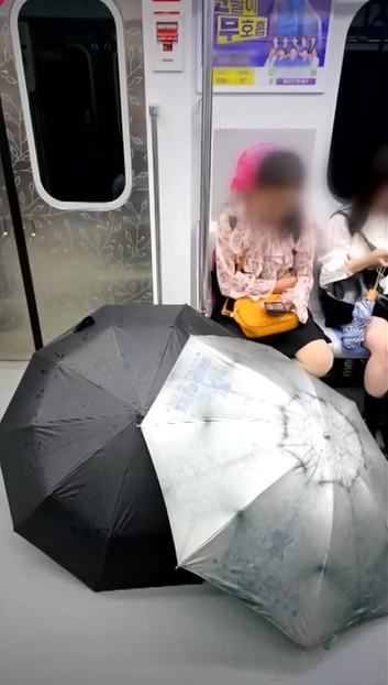 지난 5일 서울 지하철 5호선 객차 안에서 중국인으로 추정되는 여성이 임신부석에 앉은 채 젖은 우산을 펼쳐 말리고 있다. 자료 : JTBC