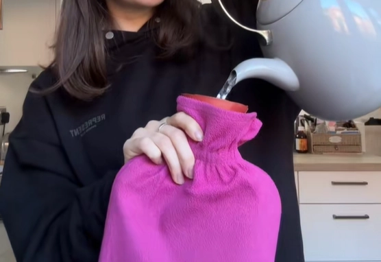 온수 주머니를 사용하는 여성. 기사와 직접적인 관련 없음. 틱톡 캡처