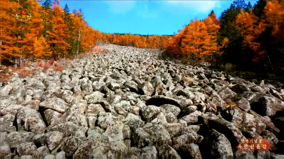 북한 조선중앙TV가 12일 방영한 함경남도 부전군 옥련산돌강의 가을 풍경. 천연기념물인 옥련산돌강은 산봉우리 암괴들이 강골짜기를 따라 이동해 깔린 것으로 너비 약 120m, 길이 약 700m에 달하며 돌밭 밑으로 물소리만 들리고 물은 보이지 않는 것으로 알려져 있다.  2025.11.12  조선중앙TV 화면