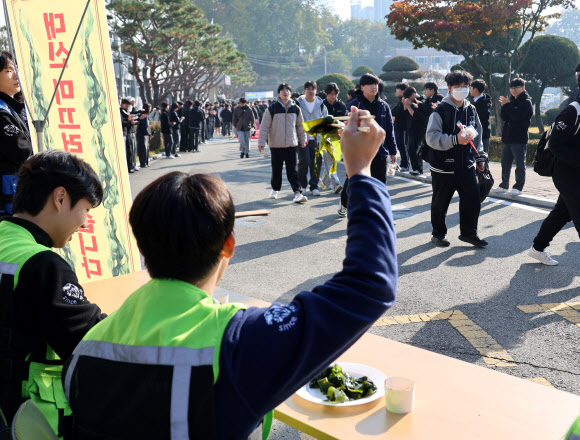 2026학년도 대학수학능력시험을 하루 앞둔 12일 청주 신흥고등학교에서 학생들이 예비소집장으로 향하는 수능생들을 응원하고 있다. 사진은 일부 학생들이 ‘선배들을 대신해 미끄러지겠다’며 미역 시식 퍼포먼스를 하고 있는 모습. 2025.11,12 연합뉴스