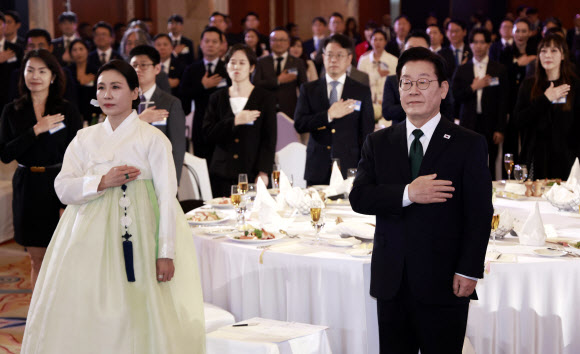 아랍에미리트(UAE)를 국빈 방문 중인 이재명 대통령과 김혜경 여사가 17일(현지시간) 아부다비의 한 호텔에서 열린 동포만찬간담회에서 국기에 경례하고 있다. 2025.11.18  연합뉴스