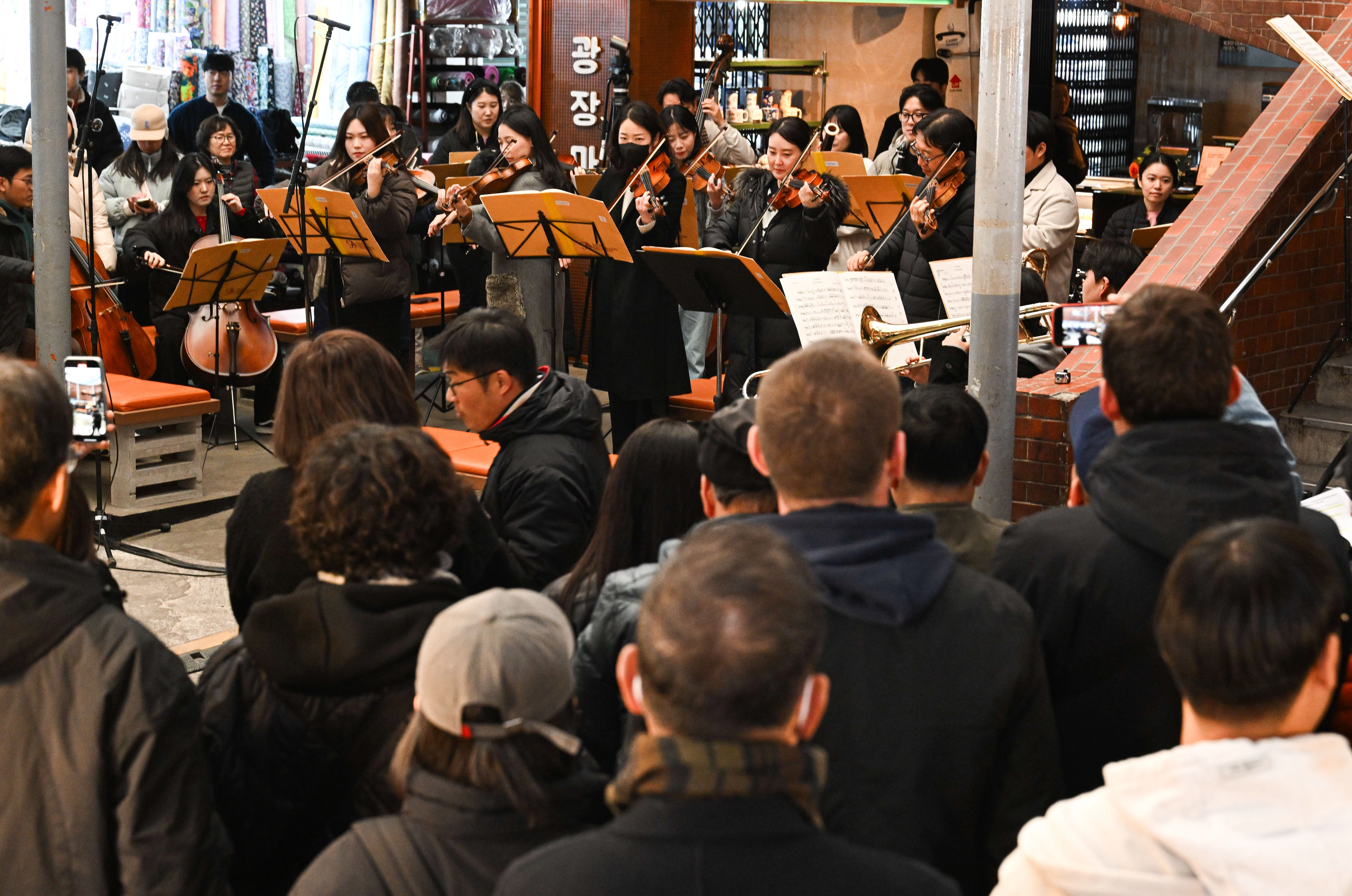 18일 서울 종로구 광장시장에서 열린 ‘2025 서울바이브’에서  지나가던 관광객들이 공연을 보고 있다.
