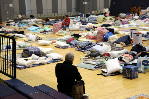 28일(현지시간) 임시 대피소가 마련된 홍콩 북부 퉁 청 거리 시민회관 강당에 화재 피해자가 앉아서 쉬는 모습. 2025.11.28 . 연합뉴스