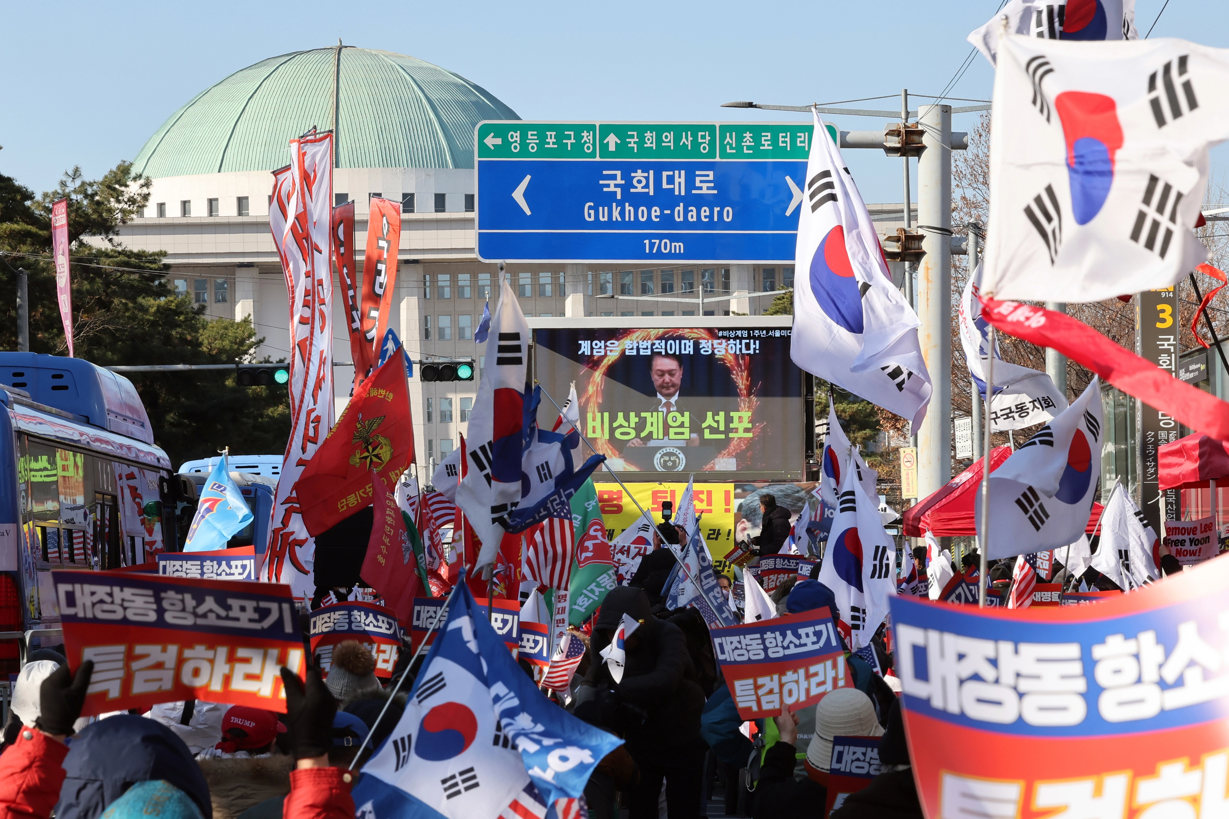 12·3 비상계엄 1년을 맞은 3일 오후 서울 영등포구 여의도 국회의사당역 앞에서 신자유연대 등 보수단체 회원들이 윤석열 전 대통령의 계엄 선포 영상을 지켜보고 있다.  2025.12.3. 뉴스1