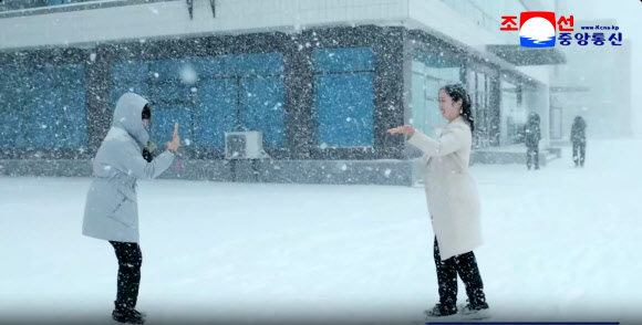 지난 4일 평양에 첫눈이 내린 가운데 한 여성이 포즈를 취하며 동료가 휴대전화로 촬영하고 있다. 이날 평양 지역 강설량은 평균 9cm를 기록했다고 조선중앙통신이 5일 보도했다. 2025.12.5  평양 조선중앙통신 연합뉴스