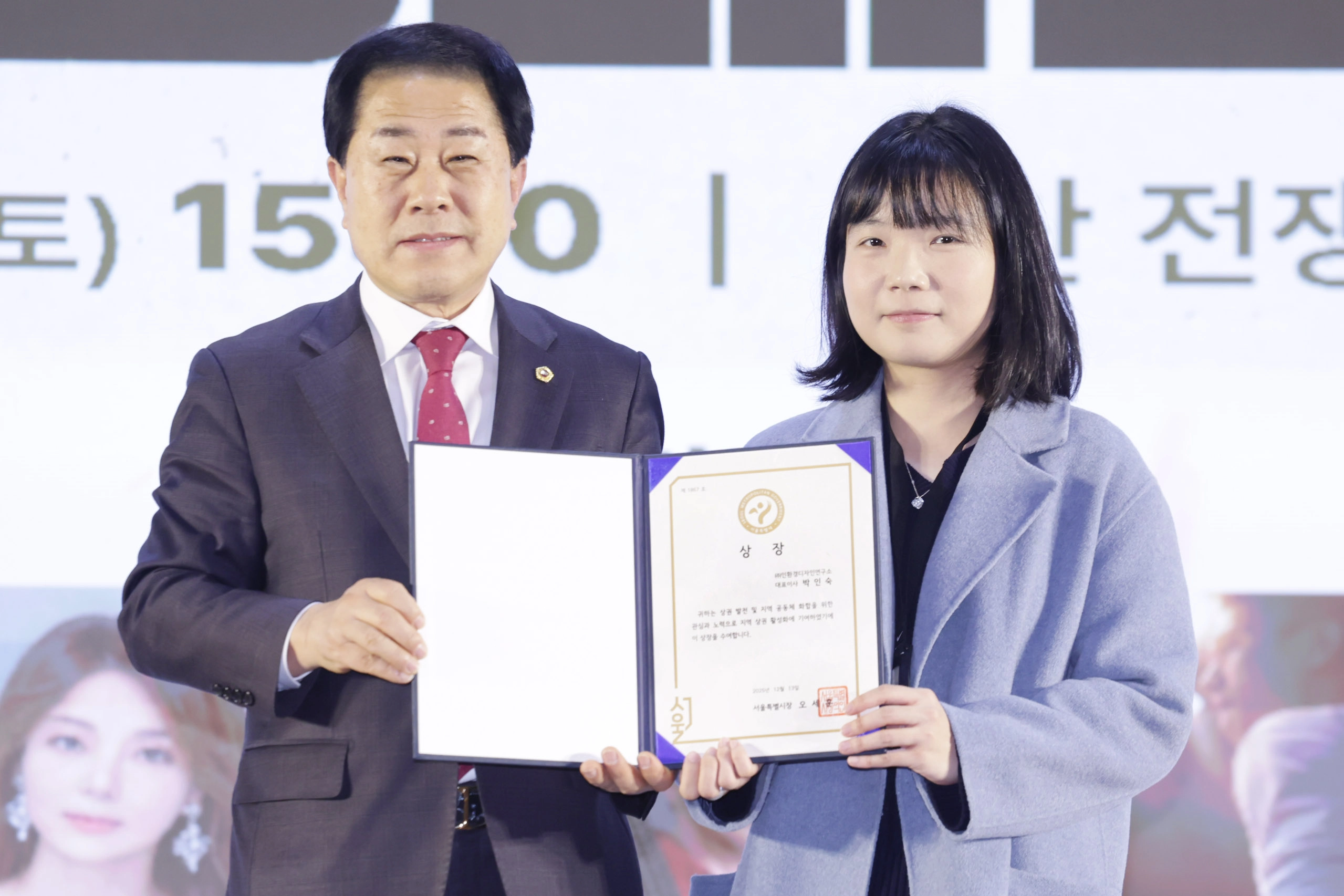 지난 13일 용산 전쟁기념관 이병형홀에서 열린 ‘2025 용산 소상공인ㆍ상점가ㆍ전통시장 상생페스타’에 참석한 김용호 서울시의원이 박인숙 인환경디자인 대표이사에게 지역 상권 발전과 공동체 활성화에 기여 공로로 ‘서울시장상’을 대리 수여하고 수상자와 기념 촬영하고 있다.