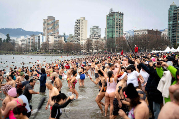 참가자들이 1일(현지시간) 캐나다 브리티시컬럼비아주 밴쿠버에서 열린 북극곰 수영 대회에서 물속으로 뛰어들고 있다. AP 연합뉴스