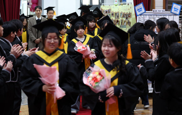 5일 대구 달서구 월곡초등학교에서 열린 졸업식 및 폐교식에서 6학년 학생들이 꽃다발을 받으며 이동하고 있다. 월곡초는 오는 3월 학령인구 감소를 이유로 폐교하며, 이날 제33회 졸업식과 함께 폐교식을 열었다. 2026.1.5 연합뉴스