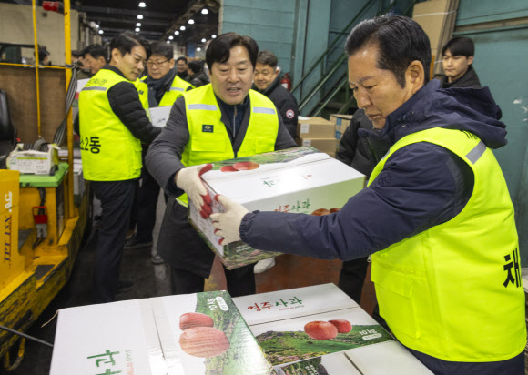더불어민주당 정청래 대표와 최고위원들이 7일 서울 송파구 가락동농수산물도매시장 중앙청과 내 사과 경매장을 방문해 경매를 마친 사과를 중간 도매인에게 배달하고 있다. 이날 민주당은 새해를 맞이해 ‘국민 곁으로! 현장 속으로!’ 현장 방문을 시작했다. 2026.1.7 연합뉴스