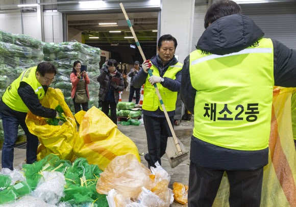 더불어민주당 정청래 대표와 최고위원, 의원들이 7일 서울 송파구 가락동농수산물도매시장 채소2동을 찾아 경매 후 남겨진 쓰레기들을 치우고 있다.  이날 민주당은 새해를 맞이해 ‘국민 곁으로! 현장 속으로!’ 현장 방문을 시작했다. 2026.1.7 연합뉴스