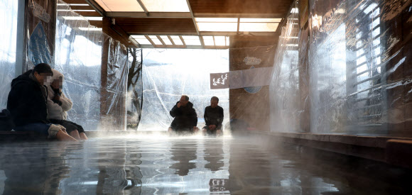 7일 낮 한파 속 충북 충주시 수안보면 온천 족욕 체험장에서 시민들이 따뜻한 온천수에 발을 담그며 한겨울 추위를 달래고 있다.  수안보 벚꽃길을 따라 조성된 이 족욕체험장에는 섭씨 47도 안팎의 온천수가 20∼40㎝ 깊이로 담겨 있다. 2026.1.7. 연합뉴스