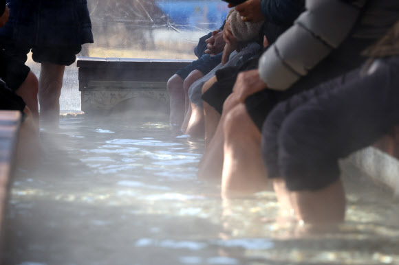 7일 낮 한파 속 충북 충주시 수안보면 온천 족욕 체험장에서 시민들이 따뜻한 온천수에 발을 담그며 한겨울 추위를 달래고 있다.  수안보 벚꽃길을 따라 조성된 이 족욕체험장에는 섭씨 47도 안팎의 온천수가 20∼40㎝ 깊이로 담겨 있다. 2026.1.7. 연합뉴스