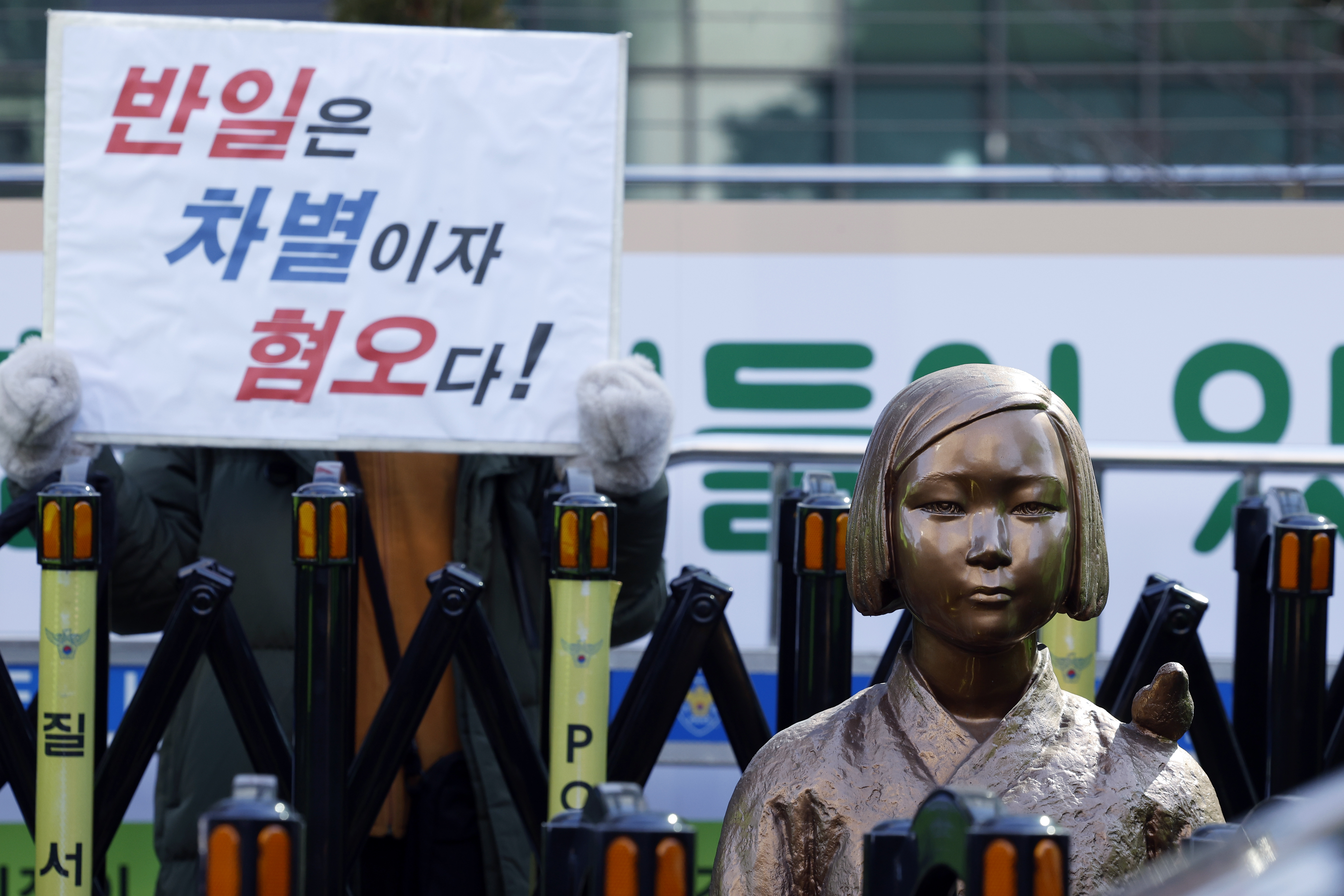 7일 낮 서울 종로구 중학동 옛 일본대사관 앞 평화의 소녀상 주위에서 극우단체 관계자가 ‘반일은 차별이자 혐오다’는 손피켓을 들고 서 있다.  이재명 대통령은 전날 엑스(X·옛 트위터)에 “이런 얼빠진…”이라며  ‘평화의 소녀상’을 대상으로 철거 시위를 벌인 극우단체 위안부법폐지국민행동을 겨냥해 “사자명예훼손”이라고 강하게 비판했다. 2026.1.7. 뉴스1