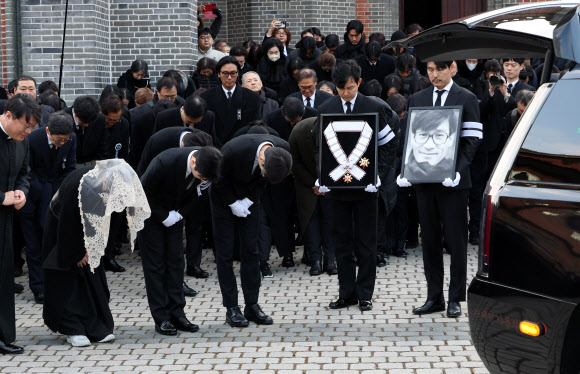 9일 서울 중구 명동성당에서 열린 배우 안성기의 장례 미사가 끝난 뒤 영결식을 위해 고인의 영정과 금관문화훈장을 든 배우 정우성, 이정재가 영결식장으로 향하고 있다. 2026.1.9. 연합뉴스
