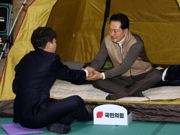 통일교·공천헌금 ‘쌍특검’ 수용을 요구하며 단식 7일 차를 맞은 국민의힘 장동혁 대표가 21일 서울 여의도 국회 로텐더홀 단식 농성장을 찾은 개혁신당 이준석 대표와 악수하고 있다. 2026.1.21  연합뉴스