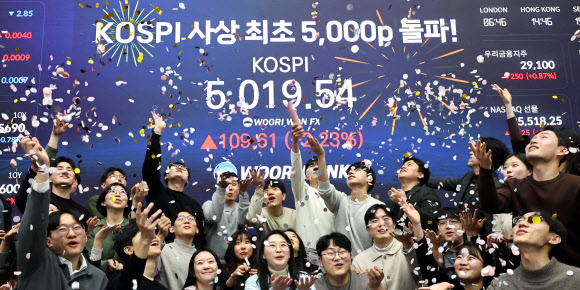 코스피 지수가 장중 사상 처음으로 5,019.54를 기록한 22일 서울 중구 우리은행 본점 딜링룸에서 딜러들이 코스피 지수 5,000선 돌파를 축하하고 있다. 2026.1.22 연합뉴스