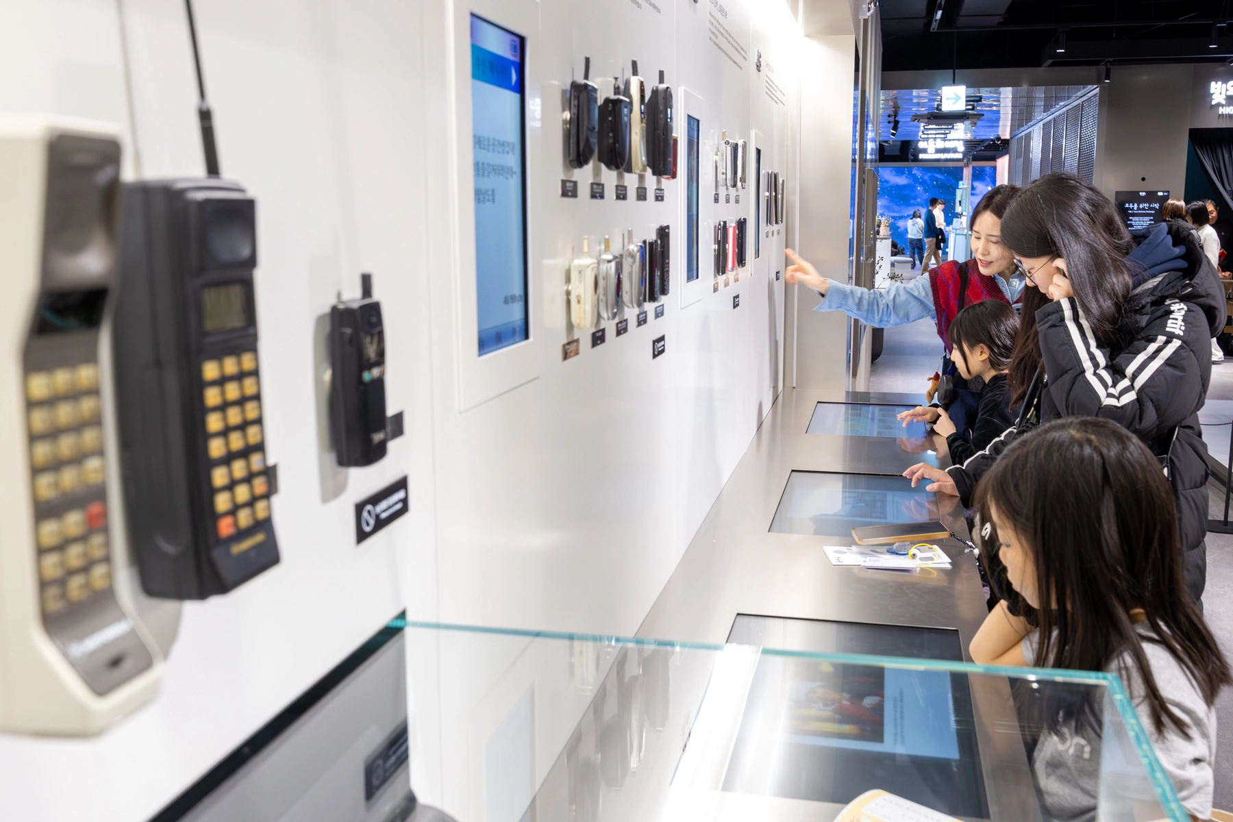 방문객들이 온마루 내 통신사료 전시 공간 ‘시간의 회랑’에서 1980~90년대 이동통신 기기 등 구세대 휴대폰을 살펴보고 있는 모습.
KT 제공