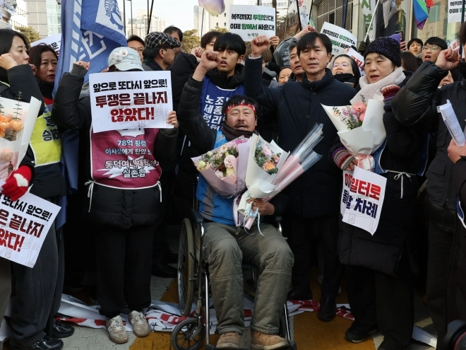 고진수 민주노총 서비스연맹 관광레저산업노조 세종호텔지부장이 14일 서울 중구 세종호텔 앞 구조물에서 내려온 뒤 휠체어에 앉아 구호를 외치고 있다.<br>연합뉴스