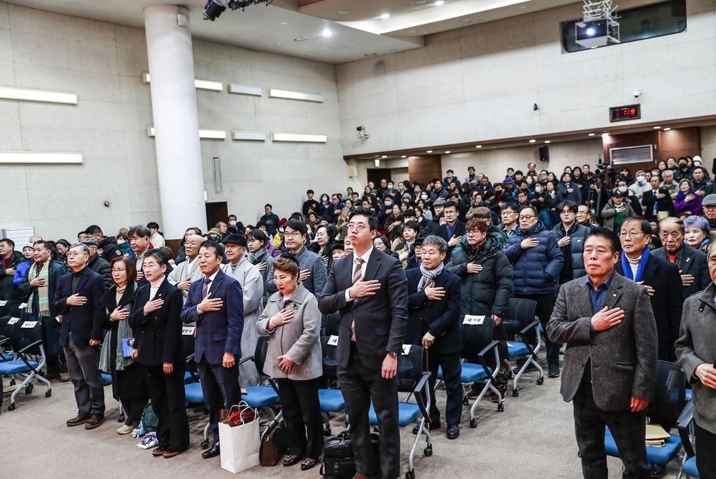 출판기념회에 참석한 참석자들이 국기에 대한 경례를 하고 있다.