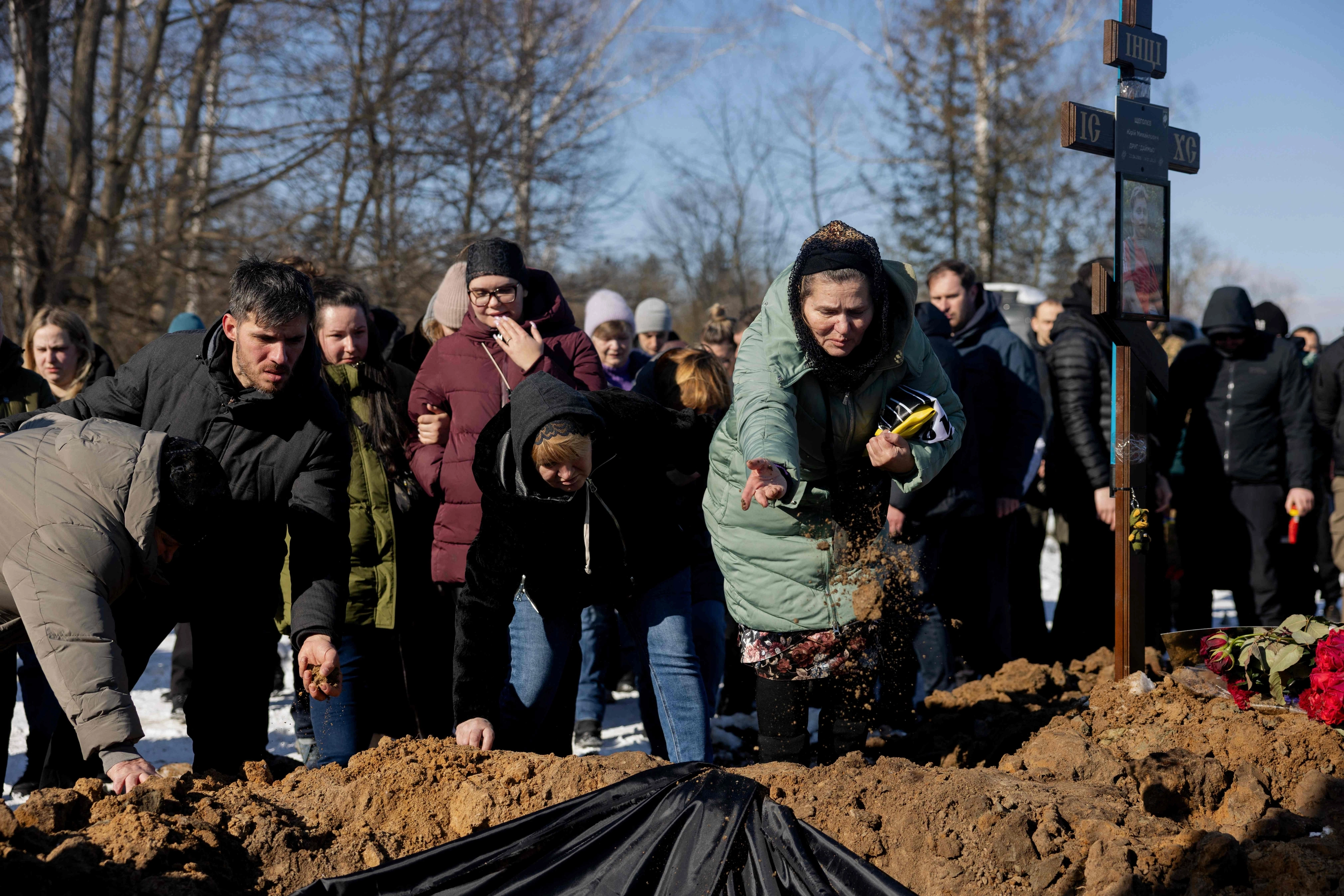 20일(현지시간) 러시아와 전쟁 중 사망한 우크라이나 병사의 장례식이 키이우에서 열린 가운데 유족과 친구 등 참석자들이 관 위에 흙을 뿌리고 있다. 2026.2.20 AFP 연합뉴스