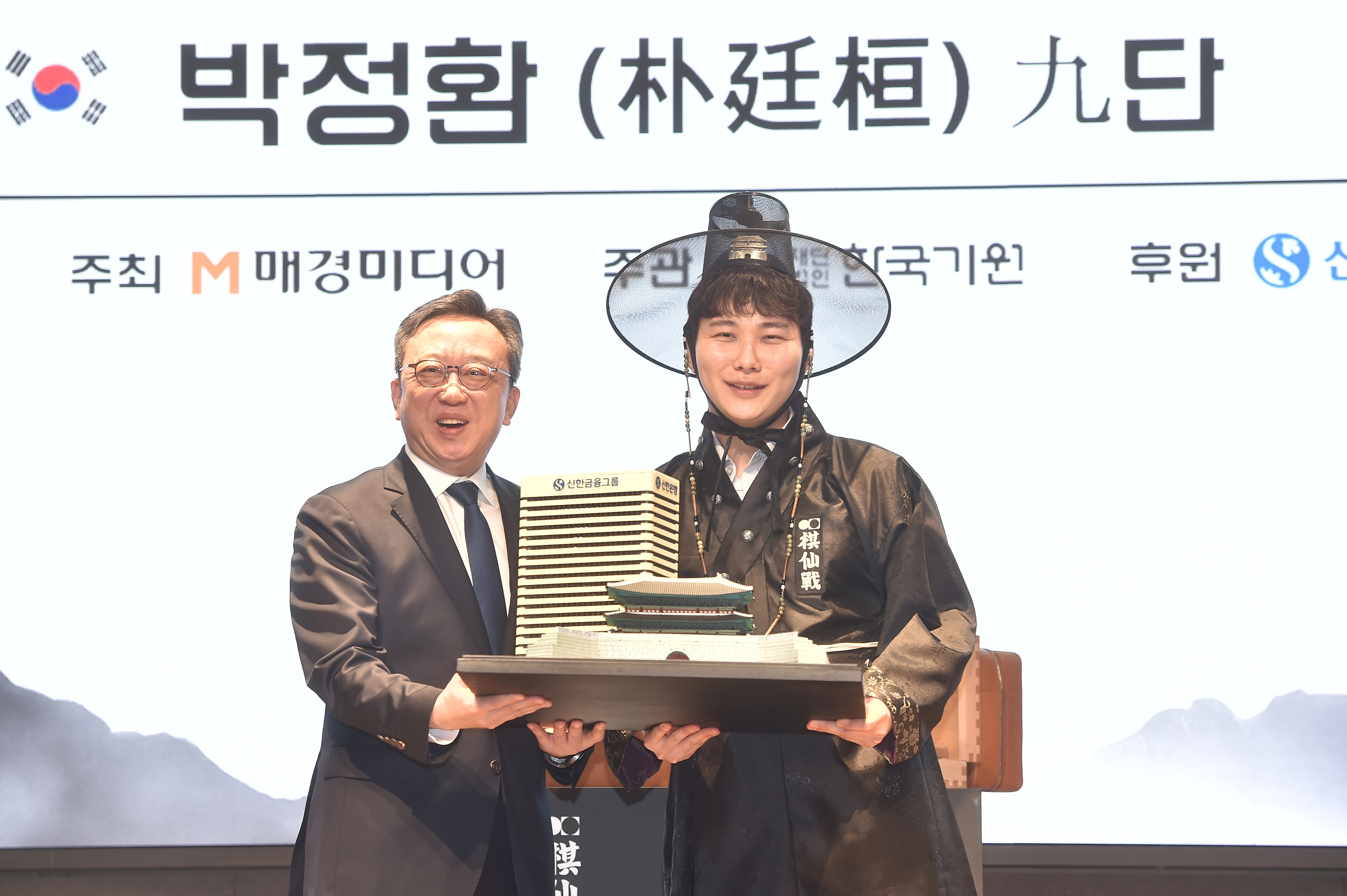 박정환(오른쪽) 9단이 27일 서울 중구 신한은행 본점 특설 대국장에서 열린 제1회 신한은행 세계 기선전 결승 3번기 최종국에서 중국의 왕싱하오 9단을 꺾고 우승한 뒤 열린 시상식에서 정상혁 신한은행장과 기념사진을 찍고 있다. 2026.2.27 한국기원 제공