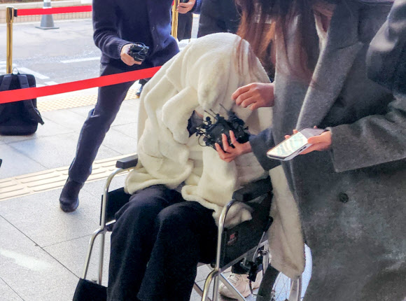 약에 취한 상태로 외제 SUV 차량을 몰고 반포대교를 달리다 한강 둔치로 추락한 운전자 A씨가 27일 서울 마포구 서부지방법원에서 열린 구속 전 피의자 심문(영장실질심사)에 옷으로 얼굴을 가리고 휠체어를 탄 채 출석하고 있다.   A씨는 지난 25일 포르쉐 SUV를 몰고 반포대교를 주행하다 난간을 뚫고 잠수교 인근 한강 둔치로 떨어져 타박상을 입었다.  A씨는 경찰 조사에서 약물을 투약하고 운전했다며 혐의를 시인한 바 있다. 2026.2.27  연합뉴스