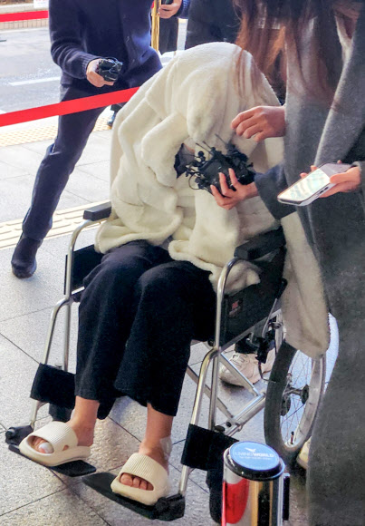 약에 취한 상태로 외제 SUV 차량을 몰고 반포대교를 달리다 한강 둔치로 추락한 운전자 A씨가 27일 서울 마포구 서부지방법원에서 열린 구속 전 피의자 심문(영장실질심사)에 옷으로 얼굴을 가리고 휠체어를 탄 채 출석하고 있다.  A씨는 지난 25일 포르쉐 SUV를 몰고 반포대교를 주행하다 난간을 뚫고 잠수교 인근 한강 둔치로 떨어져 타박상을 입었다.  A씨는 경찰 조사에서 약물을 투약하고 운전했다며 혐의를 시인한 바 있다. 2026.2.27  연합뉴스