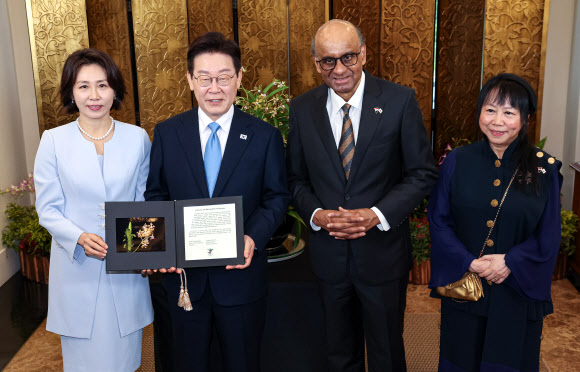 싱가포르를 국빈방문한 이재명 대통령과 김혜경 여사가 2일 싱가포르 외교부 청사에서 열린 난초 명명식에서 타르만 샨무가라트남 싱가포르 대통령, 제인 이토기 샨무가라트남 여사와 난초 증명서를 들고 기념촬영을 하고 있다. 난초 명명식은 새롭게 배양한 난초 종(種)에 귀빈의 이름을 붙이는 행사로, 난초를 국화로 삼는 싱가포르의 독특한 외교 관례다. 2026.3.2 연합뉴스