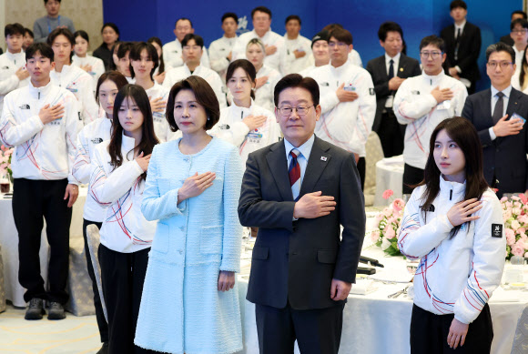 이재명 대통령과 김혜경 여사가 5일 청와대 영빈관에서 열린 2026 밀라노-코르티나담페초 동계올림픽 선수단 격려 오찬에서 국기에 경례하고 있다. 2026.3.5 연합뉴스