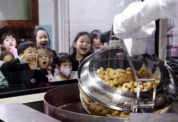 18일 경기도 수원시 대평초등학교에 설치된 거점형 학교급식 튀김 지원실에서 1학년 학생들이 튀김 조리 로봇을 살펴보고 있다. 튀김 지원실은 학생 선호도가 높은 튀김 식단을 별도 공간에서 조리한 뒤 인근 학교에 제공하기 위한 것으로 경기교육청이 전국에서 처음으로 도입한 학교급식 모델이다. 2026.3.18 [공동취재] 연합뉴스