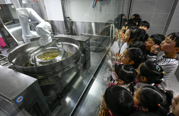 18일 경기도 수원시 대평초등학교에 설치된 거점형 학교급식 튀김 지원실에서 1학년 학생들이 튀김 조리 로봇을 살펴보고 있다. 튀김 지원실은 학생 선호도가 높은 튀김 식단을 별도 공간에서 조리한 뒤 인근 학교에 제공하기 위한 것으로 경기교육청이 전국에서 처음으로 도입한 학교급식 모델이다. 2026.3.18 [공동취재] 연합뉴스