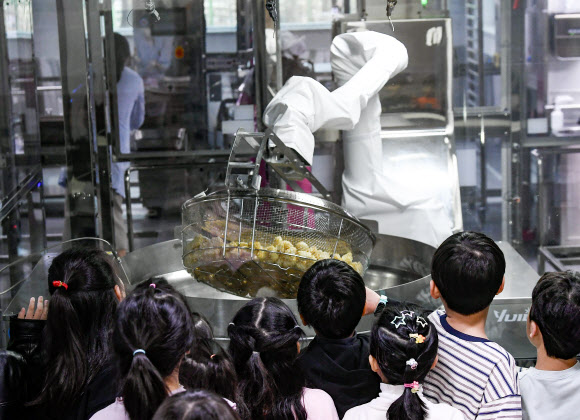 18일 경기도 수원시 대평초등학교에 설치된 거점형 학교급식 튀김 지원실에서 1학년 학생들이 튀김 조리 로봇을 살펴보고 있다. 튀김 지원실은 학생 선호도가 높은 튀김 식단을 별도 공간에서 조리한 뒤 인근 학교에 제공하기 위한 것으로 경기교육청이 전국에서 처음으로 도입한 학교급식 모델이다. 2026.3.18 [공동취재] 연합뉴스