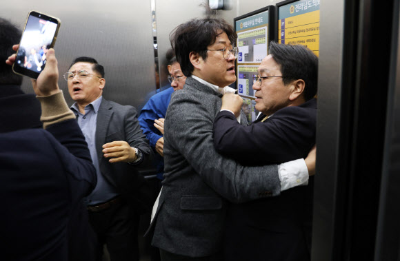 더불어민주당 전남광주특별시장 경선에 참여한 강기정 광주시장(오른쪽)이 18일 전남도의회 브리핑룸에서 서부권 비전 공약을 발표한 뒤 의대 입지 문제로 목포지역 정치인과 시민의 거센 항의를 받으며 엘리베이터에 타고 있다. 2026.3.18 연합뉴스