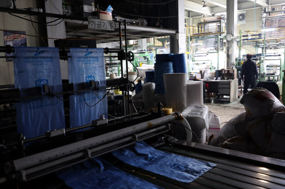 24일 중동 사태에 따른 폴리에틸렌 등 원료 수급 불안 영향으로 최근 일시적으로 인원 감축 운영에 들어간 경기 안산시의 한 비닐봉투, 종량제 봉투 제조 공장 내 가공 작업대의 불이 꺼져있다.  중동 정세 불안에 따른 나프타 도입 차질로 국내 석유화학 업체들이 감산에 나서면서 국내 플라스틱 가공업체들이 어려움에 처했다. 2026.3.24  연합뉴스