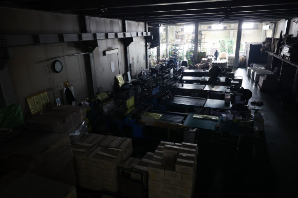 24일 중동 사태에 따른 폴리에틸렌 등 원료 수급 불안 영향으로 최근 일시적으로 인원 감축 운영에 들어간 경기 안산시의 한 비닐봉투, 종량제 봉투 제조 공장 내 가공 작업대의 불이 꺼져있다.       중동 정세 불안에 따른 나프타 도입 차질로 국내 석유화학 업체들이 감산에 나서면서 국내 플라스틱 가공업체들이 어려움에 처했다. 2026.3.24 연합뉴스