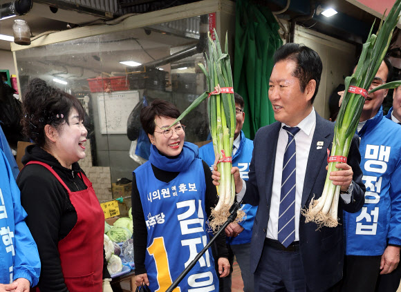 더불어민주당 정청래 대표가 25일 충북 충주시 재래시장인 자유시장을 방문, 채소가게에서 파를 들어보이며 얘기를 나누고 있다. 2026.3.25  연합뉴스