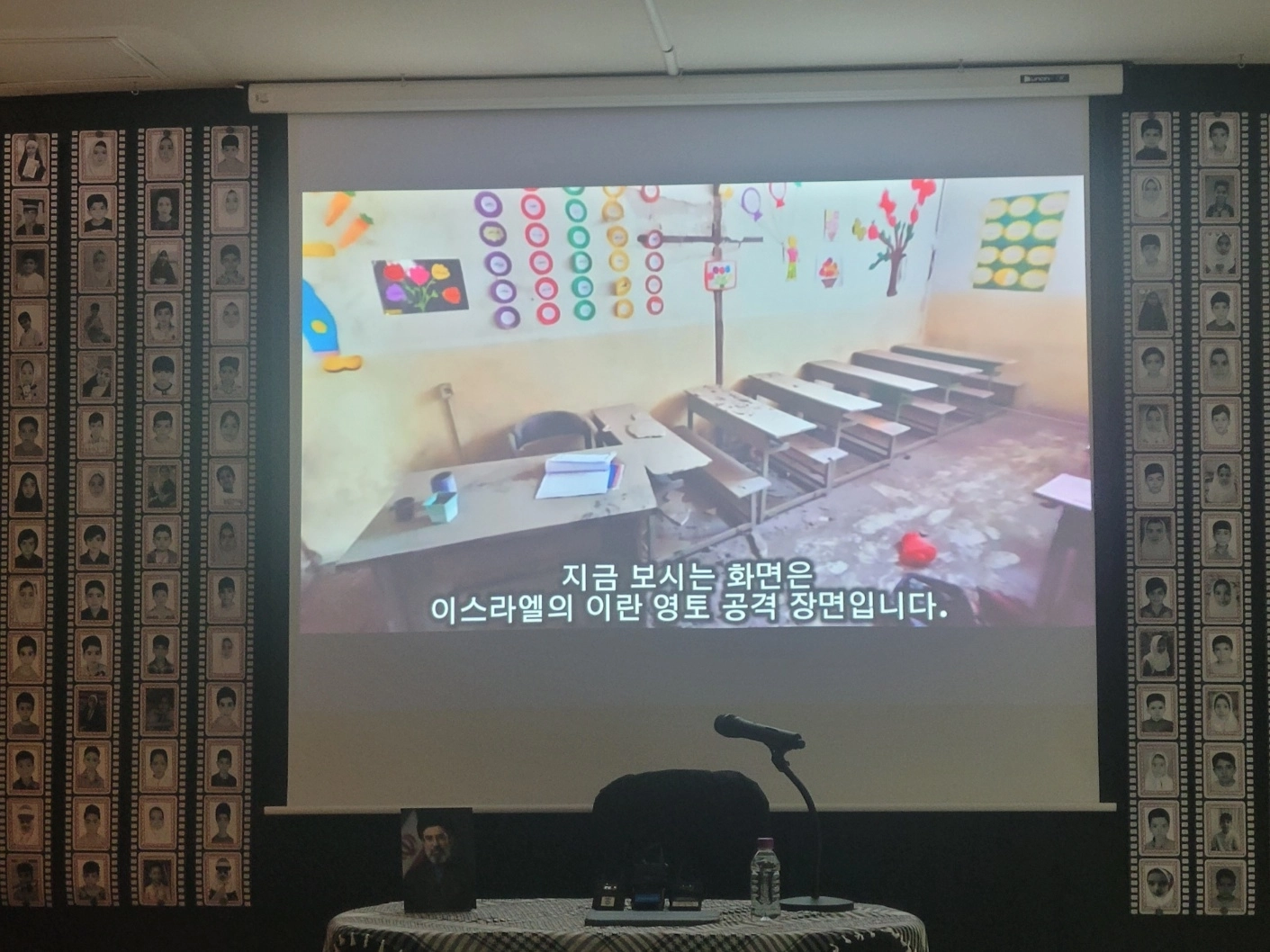 주한이란대사관에서 ‘피로 물든 천사들’ 다큐멘터리가 상영되고 있다. 화면 양 옆으로는 초등학교 폭격으로 희생된 학생들의 사진이 부착돼 있다.
이주원 기자