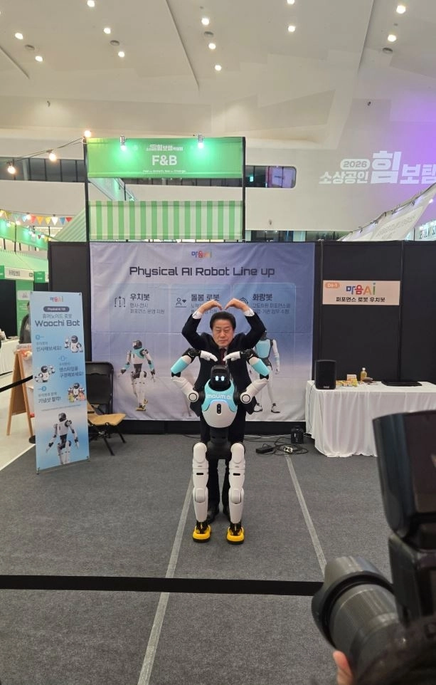 지난 26일 동대문디자인플라자(DDP)에서 개최된 ‘2026 소상공인 힘보탬 박람회’에 참석한 김용호 서울시의원이 로봇 제작업체를 둘러보고 로봇과 같이 사랑해요를 연출하며 기념촬영을 하는 모습이다.