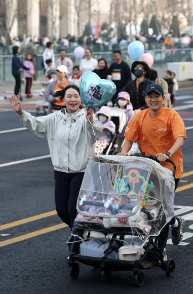 28일 서울 종로구 광화문광장에서 열린 2026 서울 유아차 런(Run) 행사에 참가한 한 가족이 반려견 사진을 풍선에 부착한 채 달리고 있다. 2026.3.28  연합뉴스