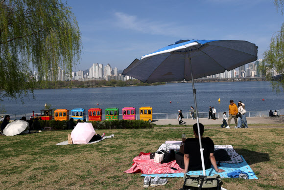맑고 따뜻한 날씨가 찾아온 12일 서울 여의도 한강공원을 찾은 시민들이 따사로운 햇살을 피하고 있다. 2026.4.12 연합뉴스
